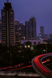 High angle view of light trails on road amidst buildings in city
