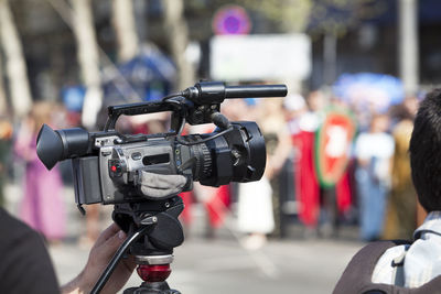 Close-up of cropped cameraman photographing crowd