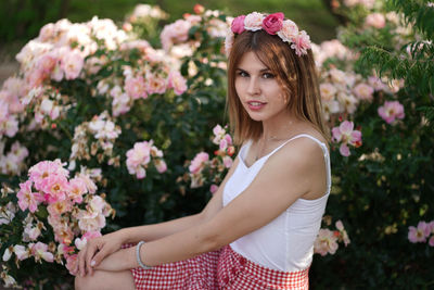 Beautiful young woman standing by flowering plants