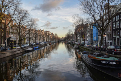 Canal amidst city against sky