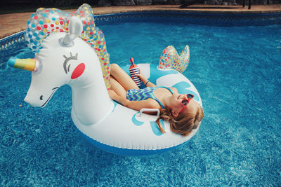 High angle portrait of boy lying on swimming pool