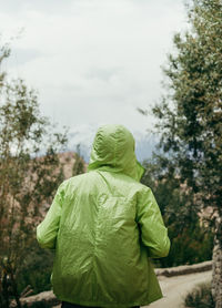 Rear view of man standing by tree against sky