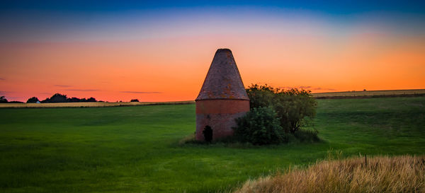 Built structure on field against sky during sunset