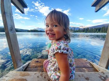 Portrait of smiling girl sitting on staircase by lake