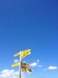 Low angle view of arrow sign against blue sky