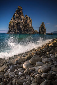 Rock formation on beach against clear blue sky