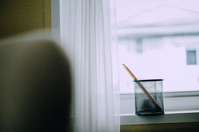 Close-up of woman looking through window at home