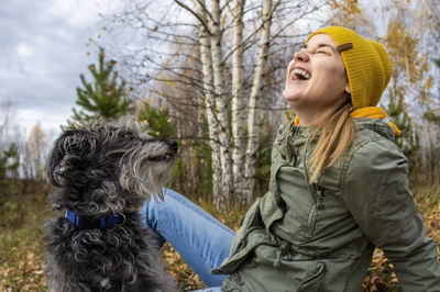 Young laughing woman playing with fluffy dog in the autumn forest. walking with pets, care 