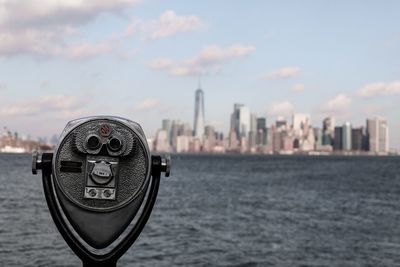 Close-up of coin-operated binoculars against cityscape