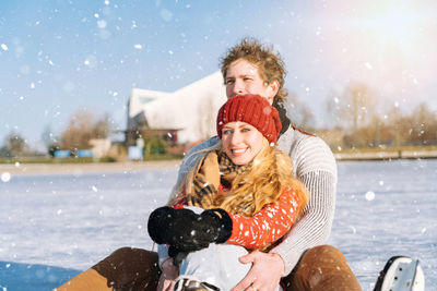 Portrait of smiling young woman with man on sledge