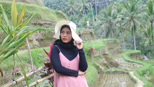 Portrait of young woman standing against tree