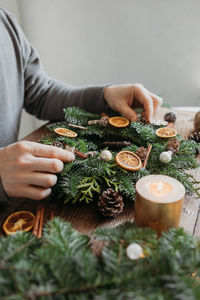 A man at home makes a christmas wreath from fresh spruce branches. decorating your home 