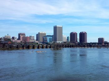 Buildings at waterfront in city against sky