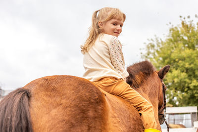 Side view of young woman with horse against sky