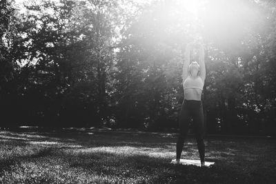 Full length of woman standing on field doing yoga 