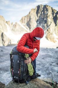 Climber packing his backpack in a mountain setting.