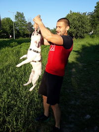 Full length of man playing dog on grass