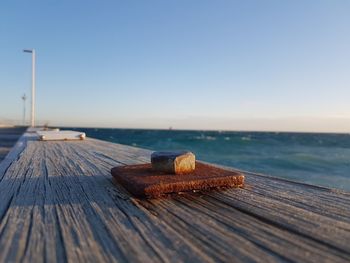 Close-up of pier over sea against clear sky