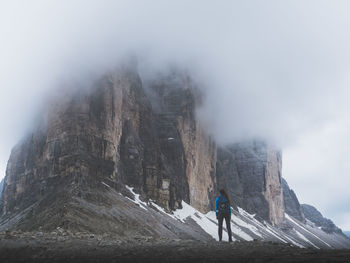 Rear view of woman standing against rock mountain