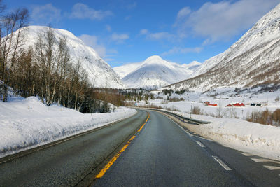 Road by snowcapped mountains against sky