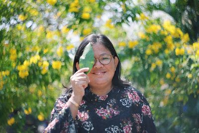 Portrait of smiling woman standing on yellow flowering plants