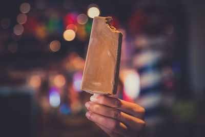 Close-up of hand holding ice cream at night