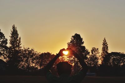 Silhouette woman by plants against sky during sunset