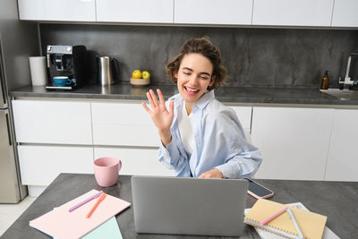 Young woman using mobile phone while sitting in office