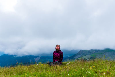 A young female hiker on a break during a hike on a cloudy summer day in the french alps