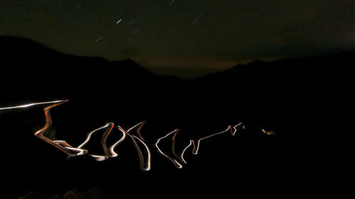 Firework display over mountains against sky at night