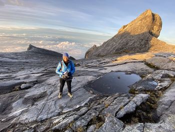 Full length of man standing on rock against sky
