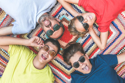 Directly above shot of siblings with father wearing sunglasses while lying on rug