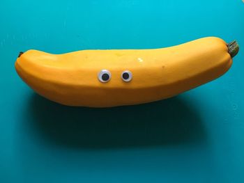 Anthropomorphic face made from banana on turquoise table