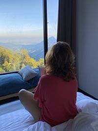 Rear view of woman looking through window