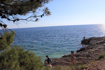 People by sea against clear sky