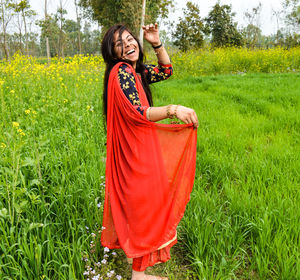 Portrait of laughing teenage girl standing on agricultural field