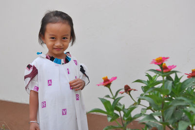 Portrait of cute girl standing against wall