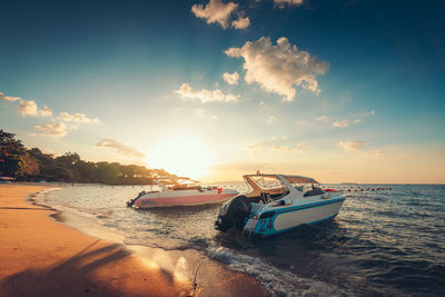 Boat moored on beach against sky during sunset