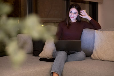 Young woman sitting on sofa at home