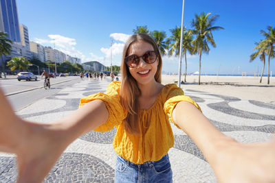 Beautiful smiling girl takes self portrait on copacabana beach promenade, rio de janeiro, brazil.