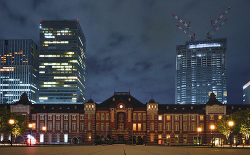 Illuminated buildings in city against sky at night