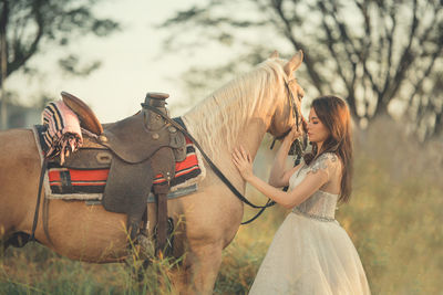 Side view of woman riding horse on field