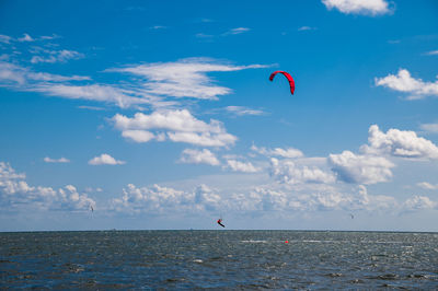 Scenic view of sea with kite surfer against sky