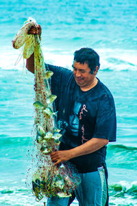 Man holding fish while standing in sea