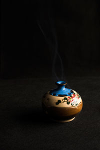 Smoke emitting from pot against black background