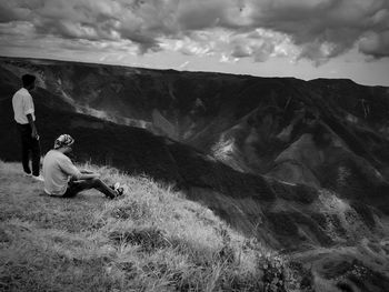 People sitting on mountain against sky