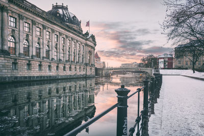 Spree river by bode museum against sky during winter
