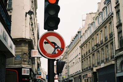 Low angle view of no left turn sign by buildings in city against sky