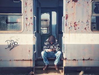 Full length of man using phone while sitting on train