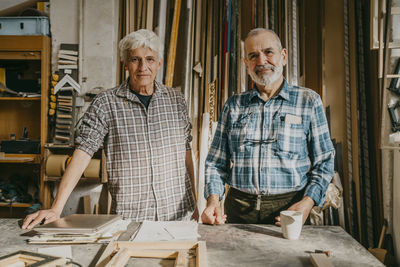 Portrait of confident senior male entrepreneurs standing at carpentry workshop